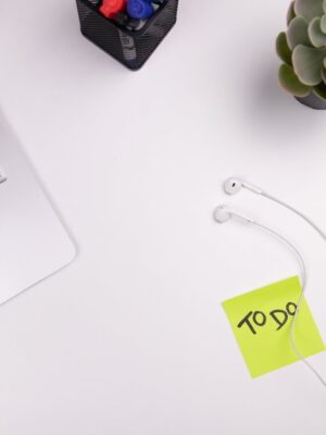 Todo list sticker post-it on a white table with earphone cables and a MacBook Air laptop